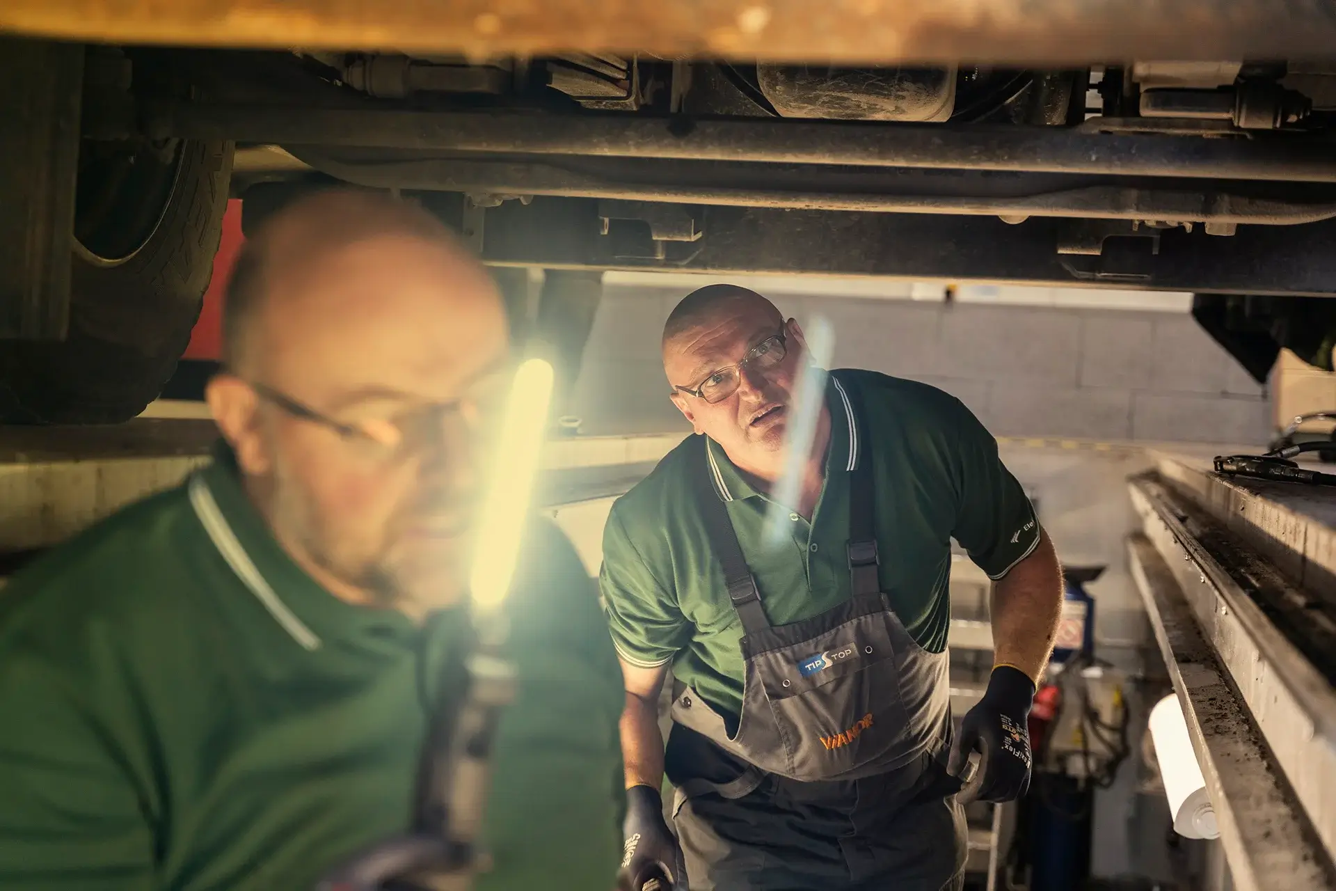 dva pracovníci zkoumají spodek auta
